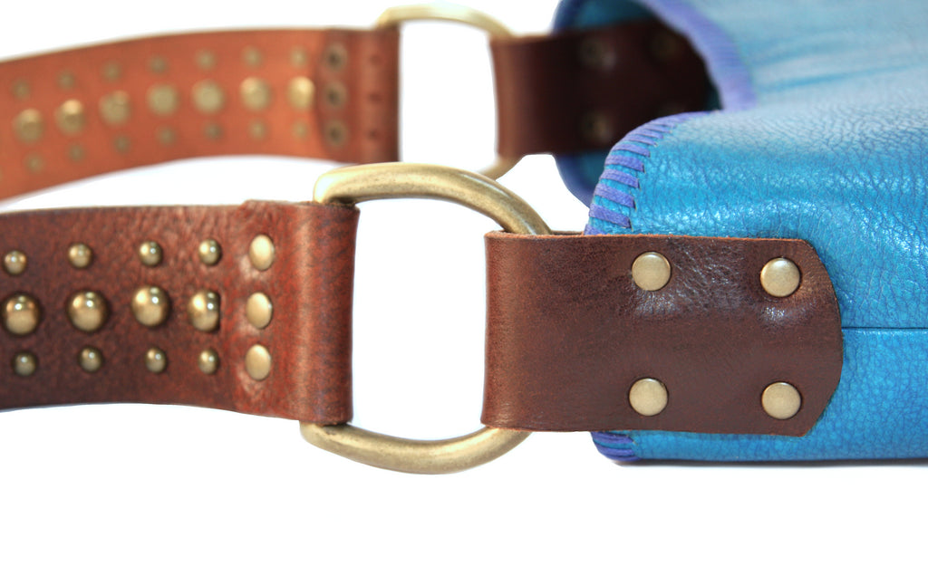 brass studded vintage belt shoulder strap with vintage hardware D ring attaching it to peacock blue handbag close up