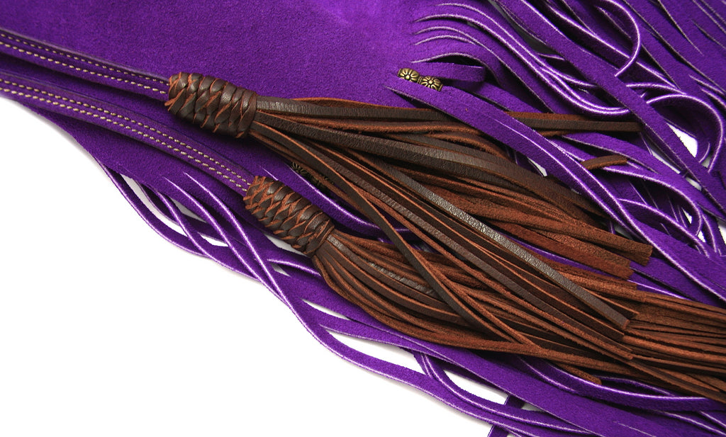 close up of long brown leather tassels attached to drawstring on purple suede fringe handbag