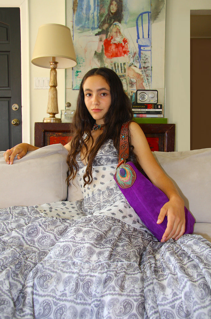  girl sitting on couch holding purple suede handbag in a New York loft