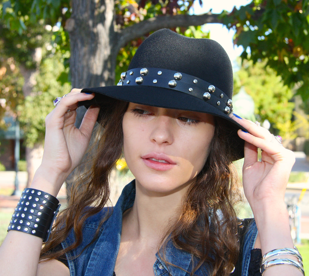 woman at park wearing black fedora hat with black leather studded hat band