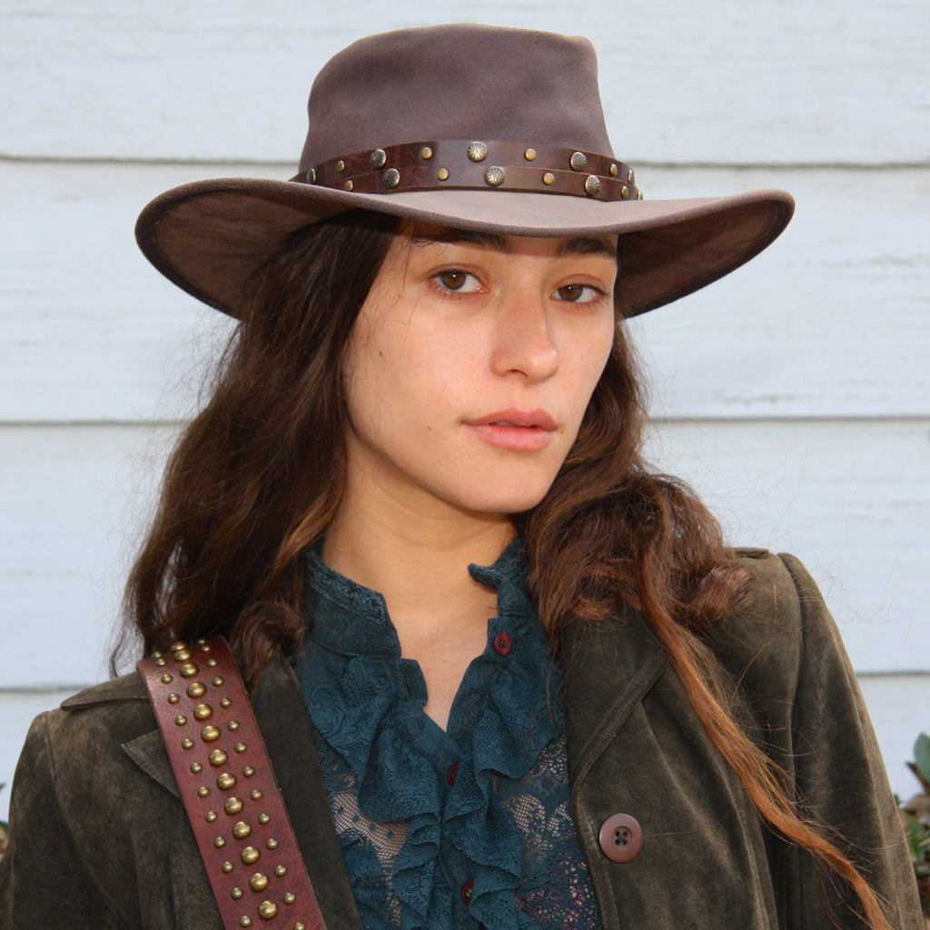 beautiful girl wearing teal lace blouse under an olive green Suede jacket also wearing a leather cowboy hat with double strap brown leather hat band with antiqued brass studs