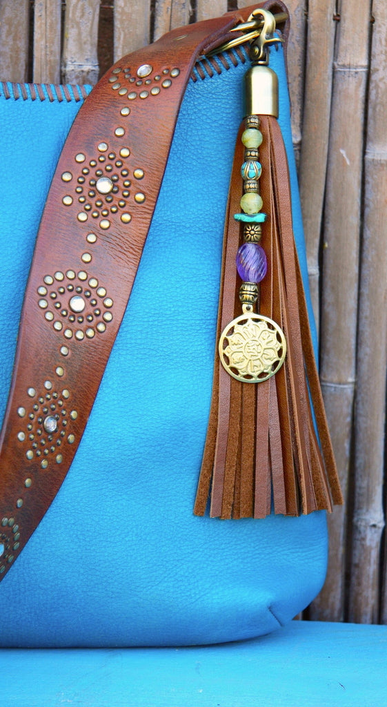 Brass tibet prayer wheel pendant on beaded strand with semi precious stones connected to brown leather tassel key fob purse charm hanging from turquoise purse 