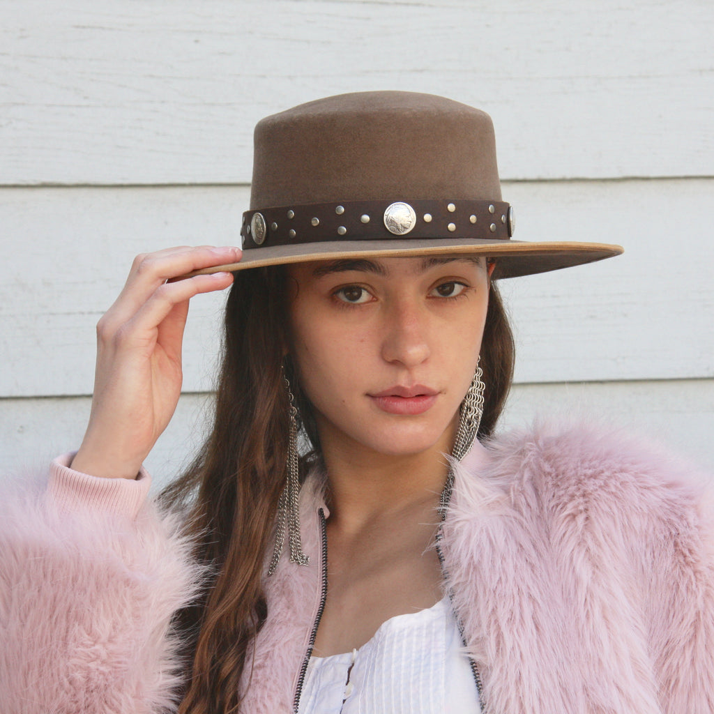 Girl wearing pink faux fur jacket and tan beaver felt bolero hat with 1 inch thick brown distressed leather hat band with buffalo nickel conchos and studs 