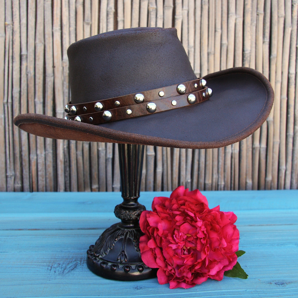 brown double strap hatband with large silver studs on leather cowboy hat with bamboo background